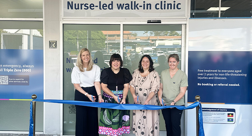 Four women stand ready to cut a blue ribbon across the doors of a shop front reading Nurse-led walk-in clinic