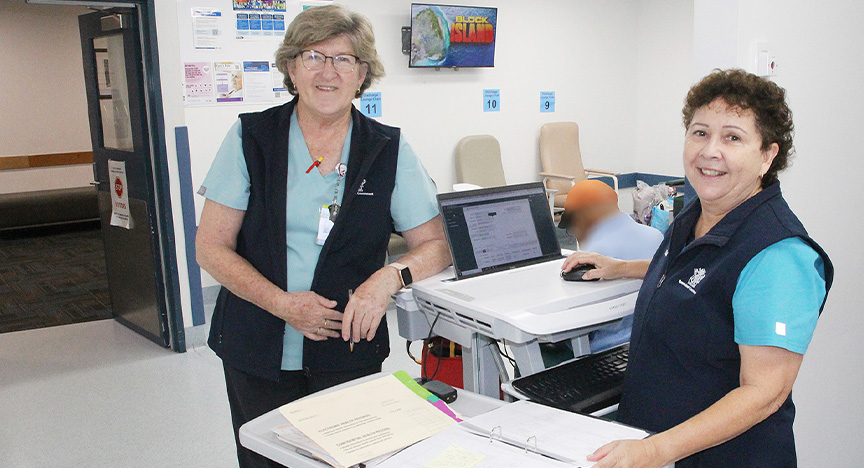 Clinical Nurse Teena Buchanan and Endorsed Enrolled Nurse Jean Olsson stand smiling in a hospital discharge lounge. 