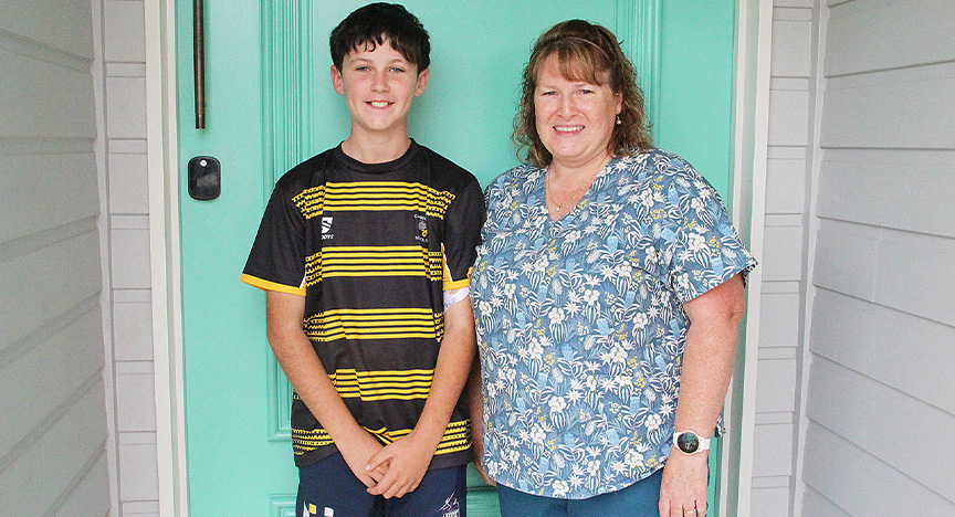 Patient Vann Breingan and Hospital in the Home nurse Mandy stand in front of Vann's front door and smile at camera.