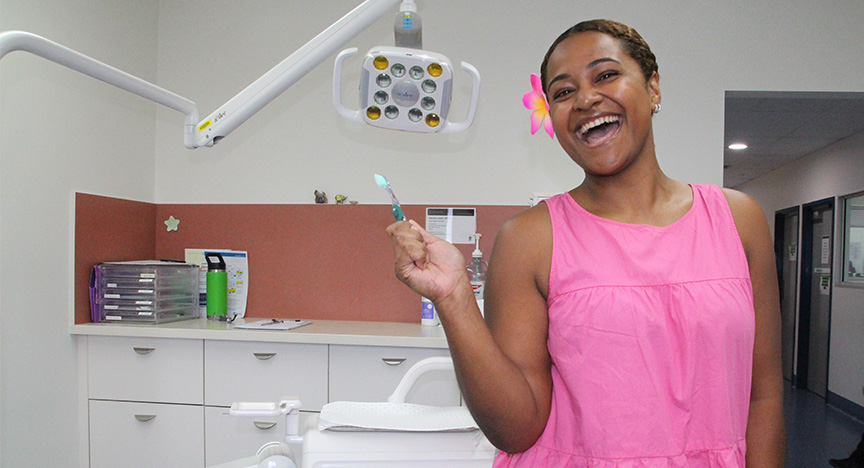 Smiling graduate dentist holding a toothbrush in a dental clinic room at Rockhampton Hospital 