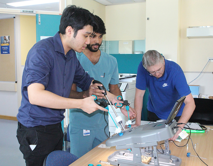 Two medical interns from CQ Health use an educational tool to do training. They are supervised by a doctor.