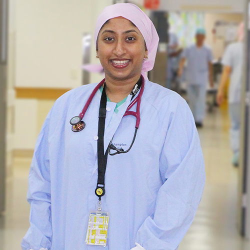 Doctor wearing scrubs smiling at the camera, standing in a Rockhampton Hospital corridor.