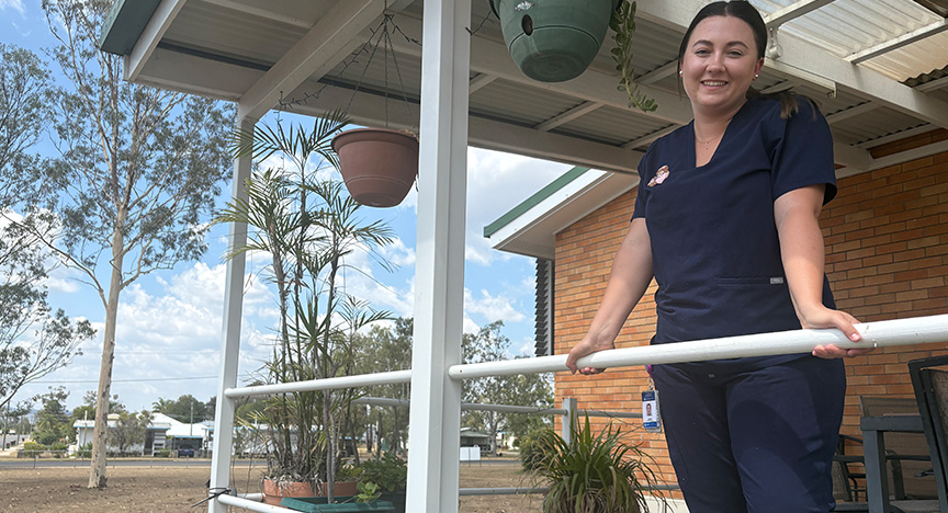 A nurse standing on a balcony among the trees at Biloela Hospital